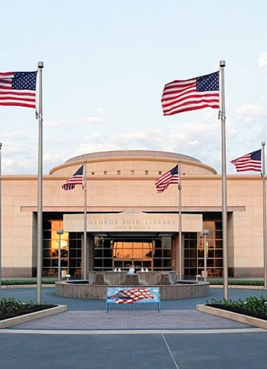 The Arbors at Wolf Pen Creek apartments The entrance of George Bush Library with multiple American flags in front.